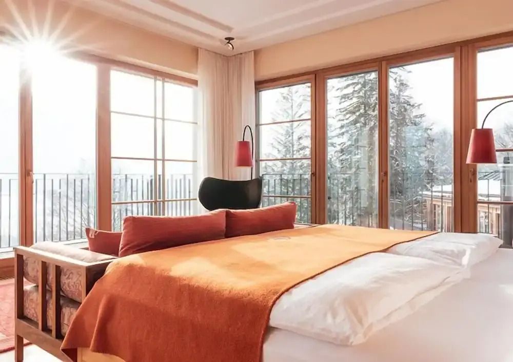 Helles Schlafzimmer mit großem Doppelbett und Blick auf verschneite Bäume.
