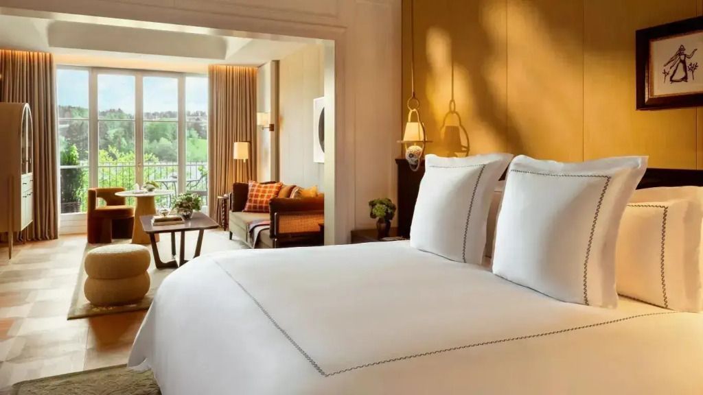 Elegantes Doppelbett in einer Junior-Suite mit Blick auf einen Balkon und Sitzbereich