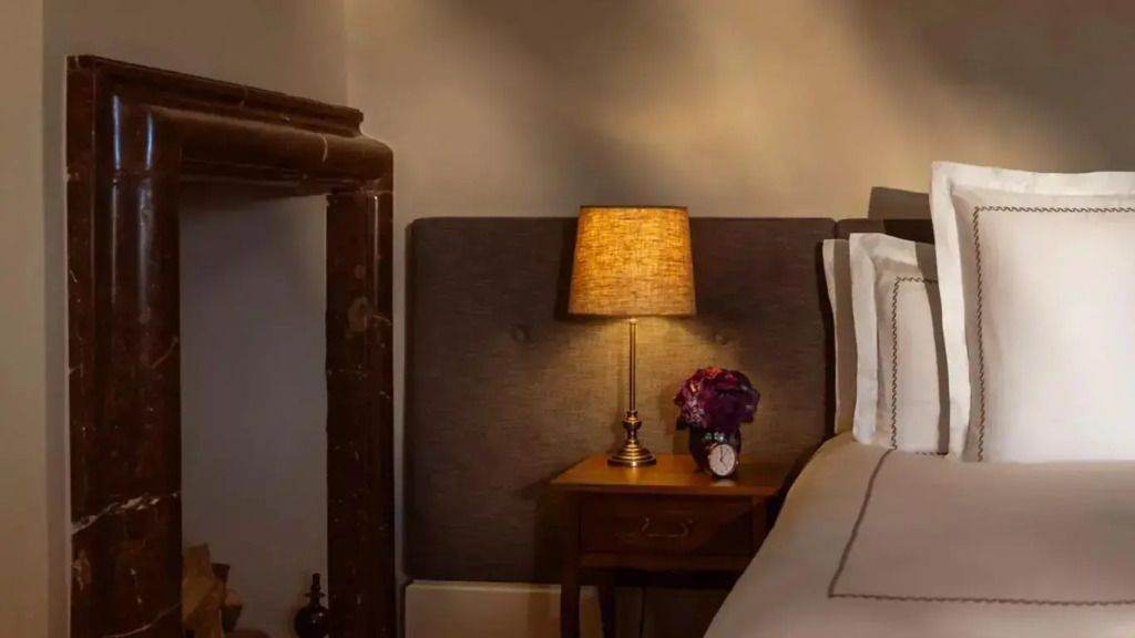Detailaufnahme eines Nachttischs im Hotelzimmer. Elegante Lampe und dekorative Uhr.