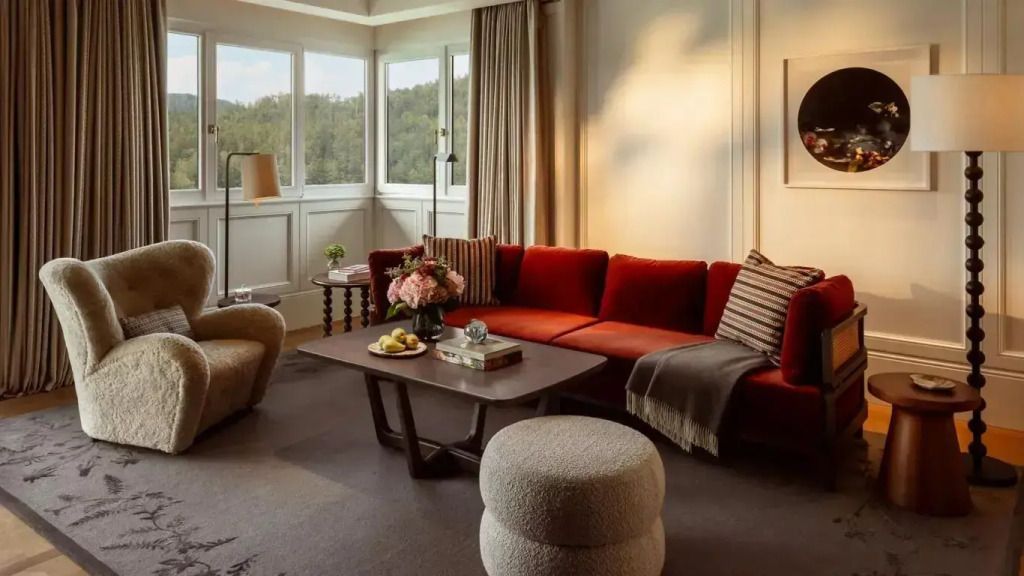 Wohnzimmer mit rotem Sofa, Fenster und eleganter Einrichtung, Blick auf Landschaft.