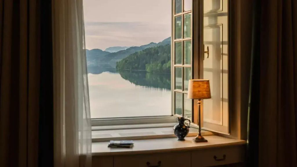 Weitläufiger Ausblick auf den See durch ein offenes Fenster mit eleganter Dekoration im Vordergrund