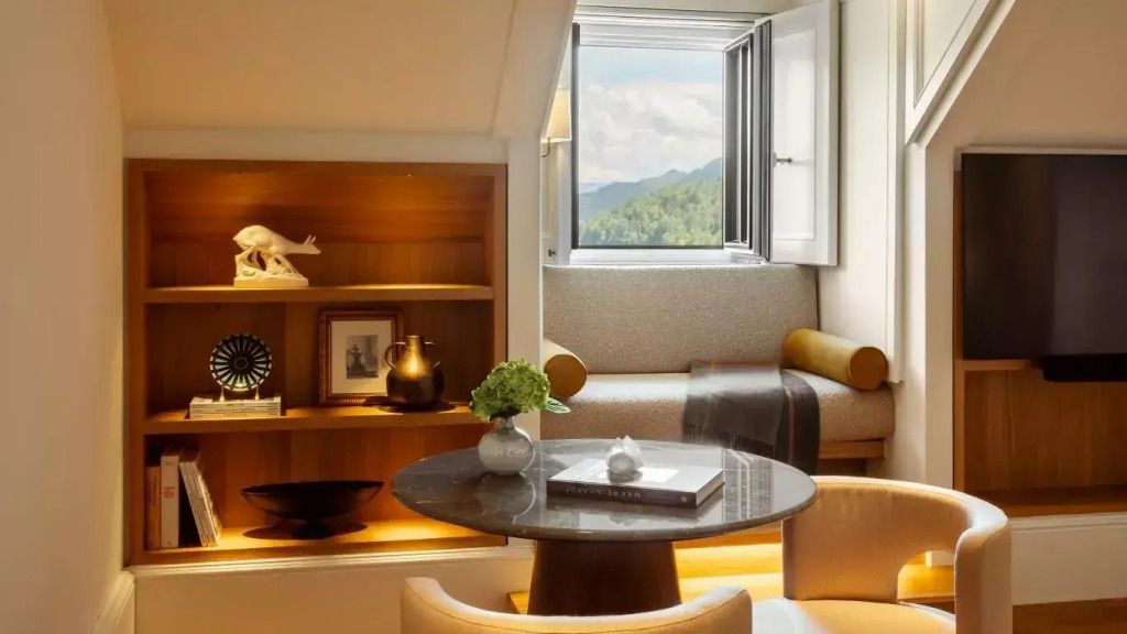Gemütlicher Sitzbereich mit geöffnetem Fenster und dekoriertem Regal in einer Suite