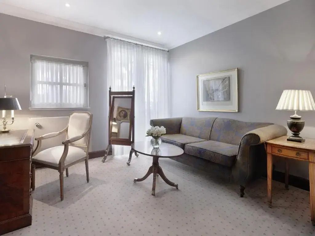 Helles Wohnzimmer mit Sofa, Sesseln und einem eleganten Tisch.