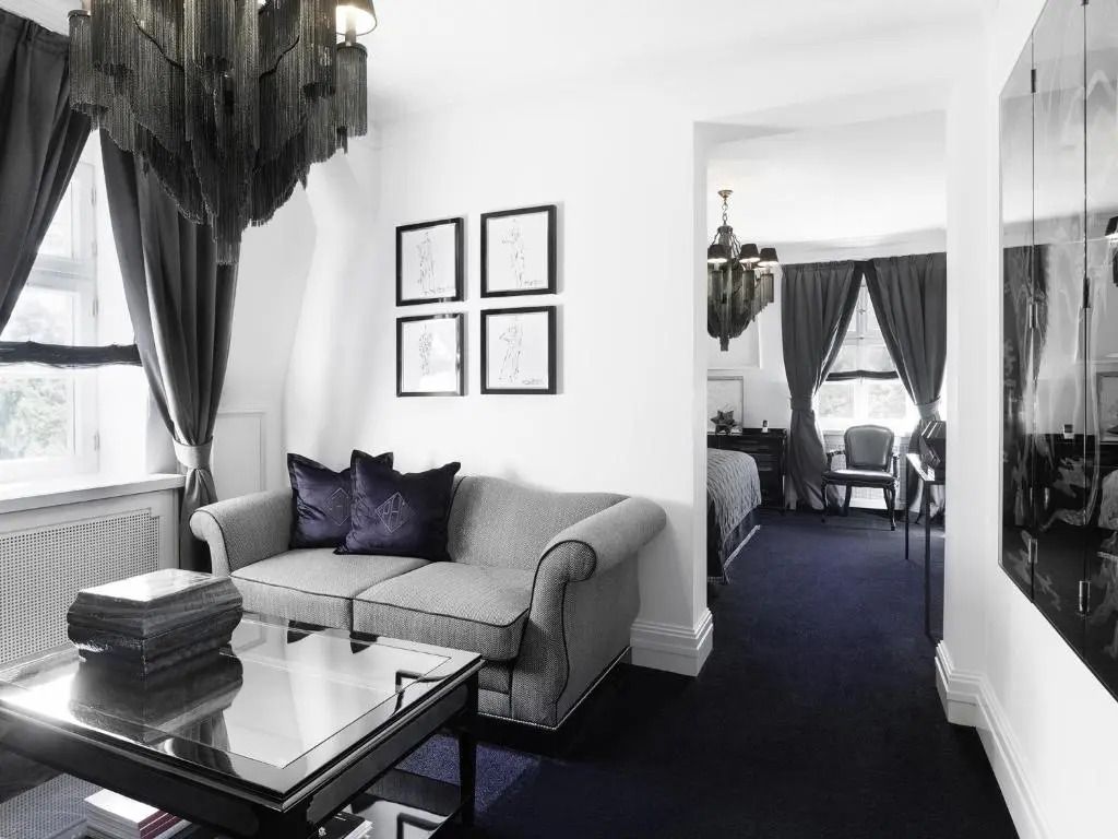 Wohnbereich mit grauem Sofa und dunklem Teppich in einer stilvollen Suite