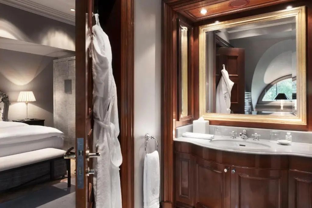 Hochwertiges Badezimmer mit Holzvertäfelung und großem Spiegel in der Suite