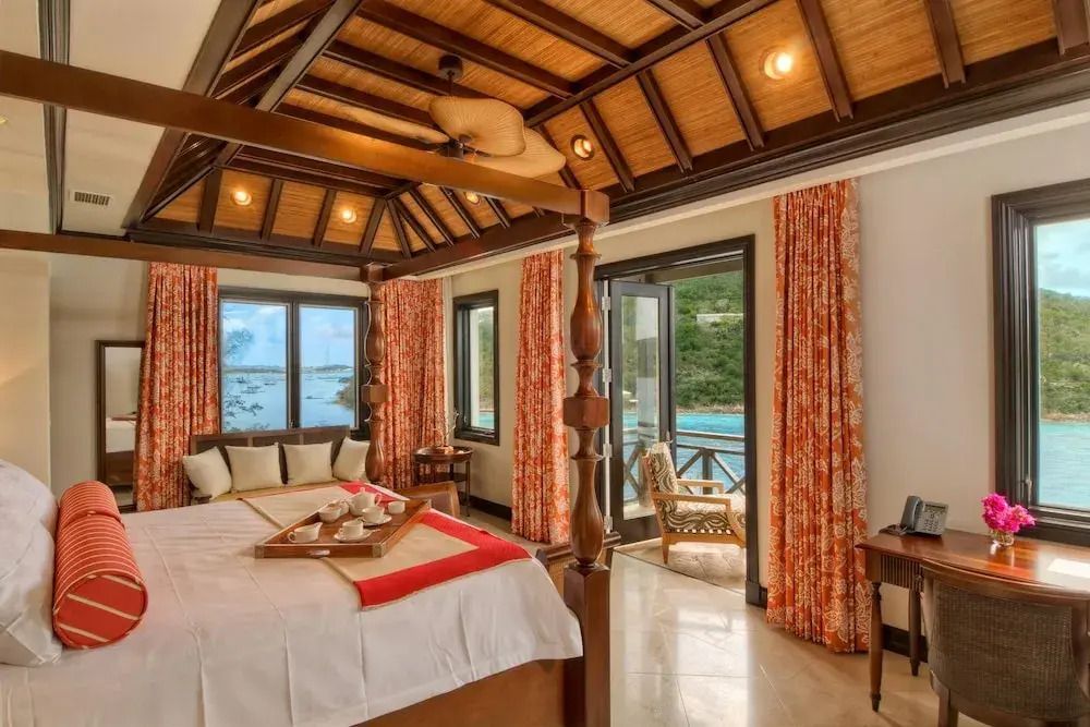 Gemütliches Schlafzimmer in einer Villa mit Holzbalken und Meerblick vom Balkon.