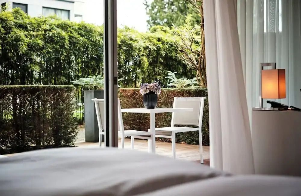 Blick vom Bett auf den Balkon eines Superior Doppelzimmers mit Tisch und Pflanzen.