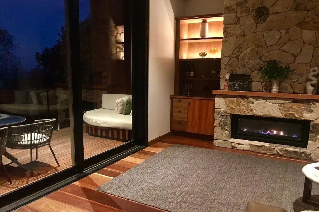 Gemütlicher Wohnbereich mit Kamin und Zugang zu einer Terrasse am Abend