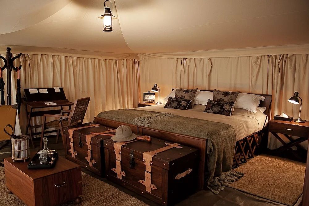 Elegantes Doppelbett in einem luxuriösen Zelt mit rustikalen Truhen und sanfter Beleuchtung
