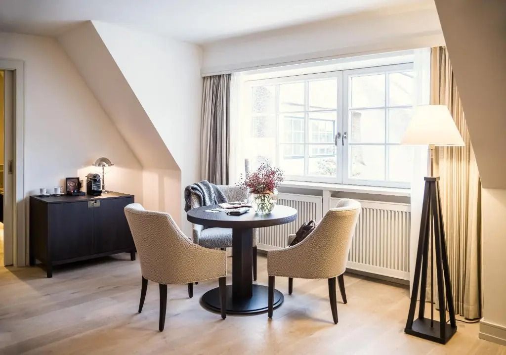 Gemütliche Sitzecke mit Tisch und Stühlen neben einem Fenster in der Junior-Suite