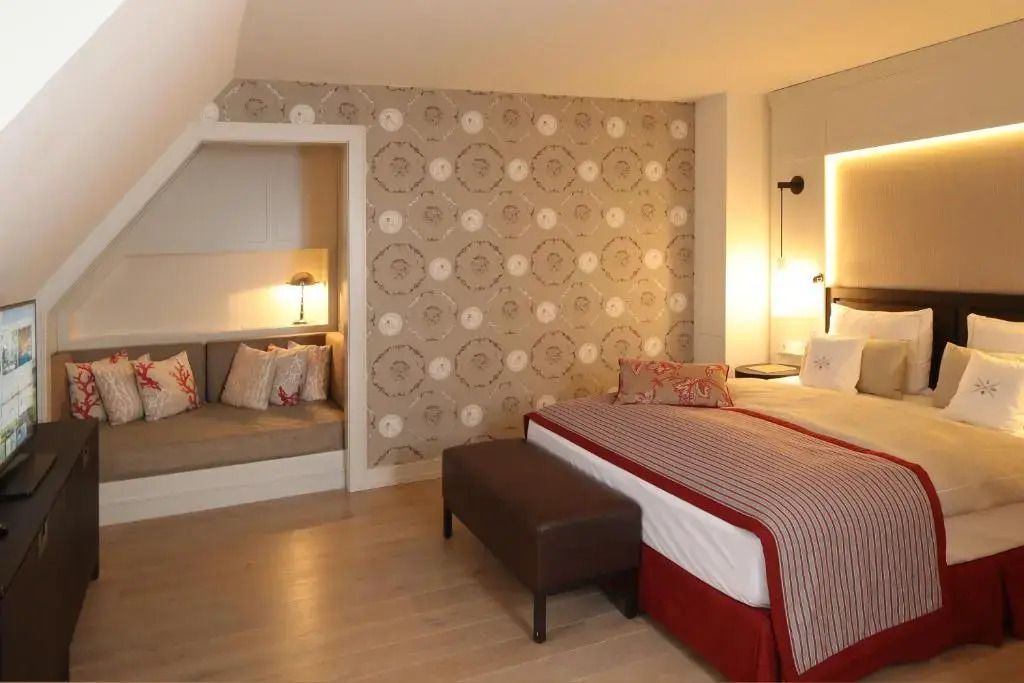 Doppelbett im Standard-Doppelzimmer mit stilvoller Tapete und Leseecke.
