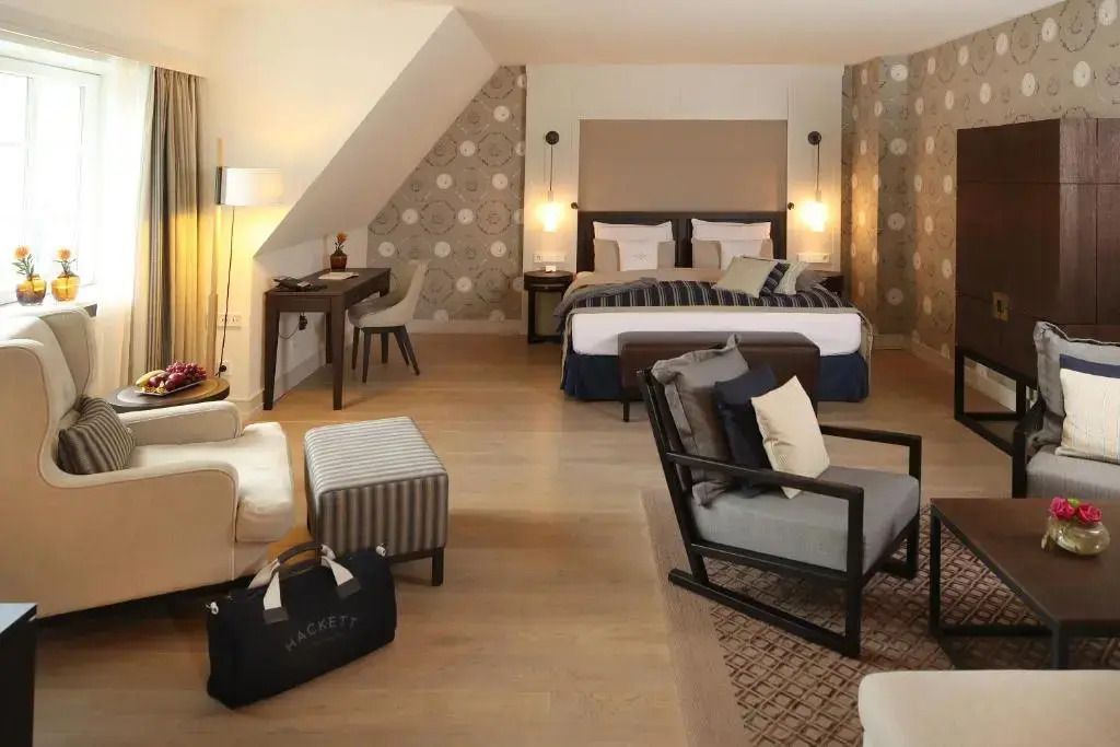 Großes Zimmer mit Doppelbett und Sitzmöglichkeiten in elegantem Design.