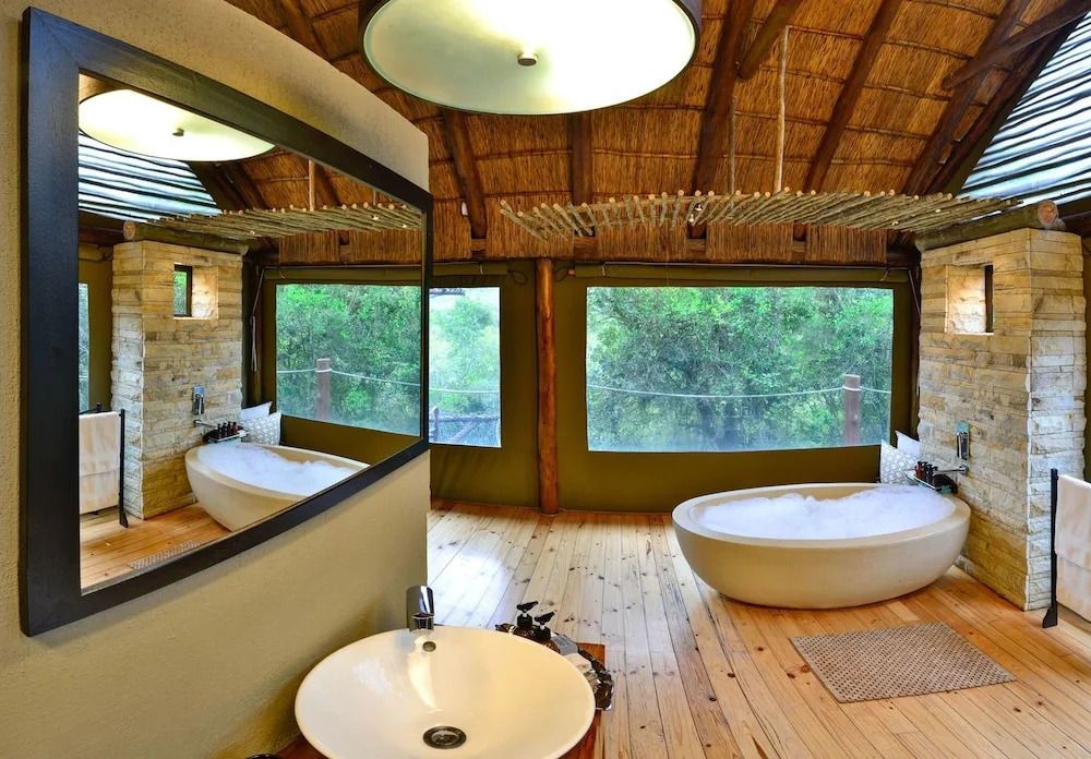 Luxuriöses Badezimmer mit freistehender Badewanne und Blick ins Grüne