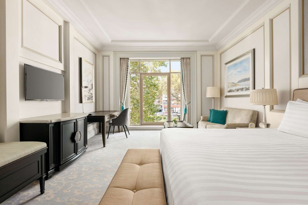 Geräumiges Zimmer mit Doppelbett und Aussicht auf die Stadt durch große Fenster