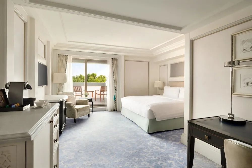 Elegantes Hotelzimmer mit Doppelbett und Balkonblick auf Bäume