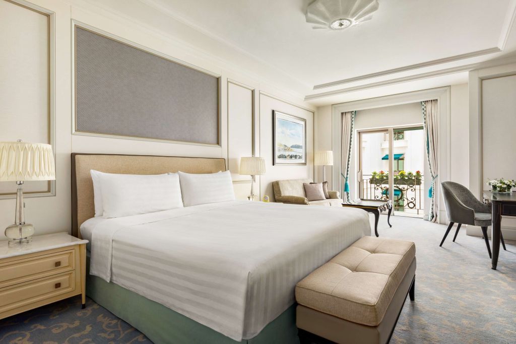 Geräumiges Hotelzimmer mit großem Bett und eleganter Einrichtung, Blick auf Balkon.
