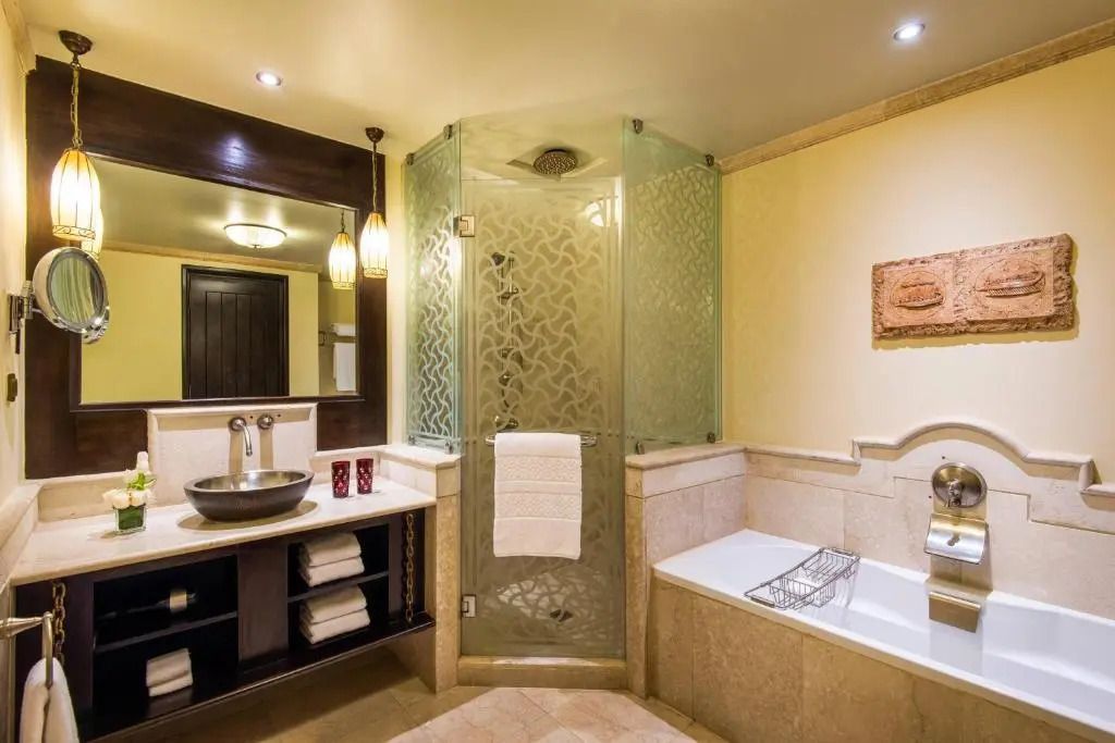 Modernes Badezimmer mit Glasdusche und Badewanne im Deluxe Zimmer des Sharq Village & Spa.
