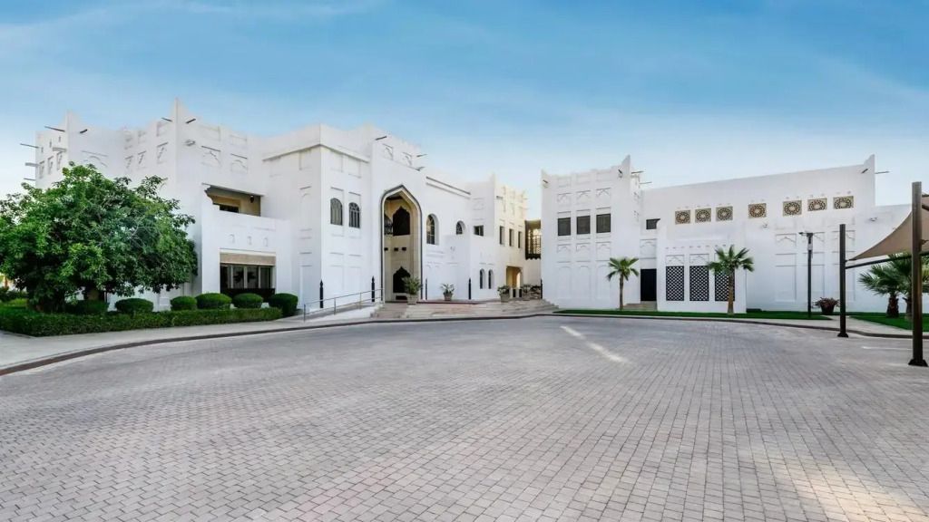 Weiße, elegante Fassade des Sharq Village & Spa unter klarem Himmel