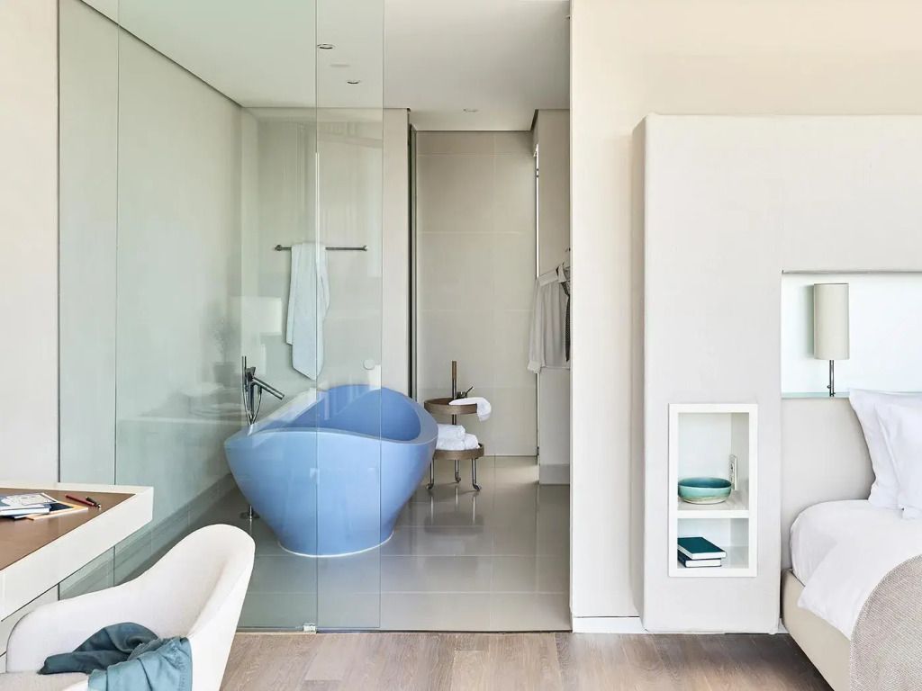 Luxuriöses Badezimmer mit freistehender blauer Badewanne und Glaswand
