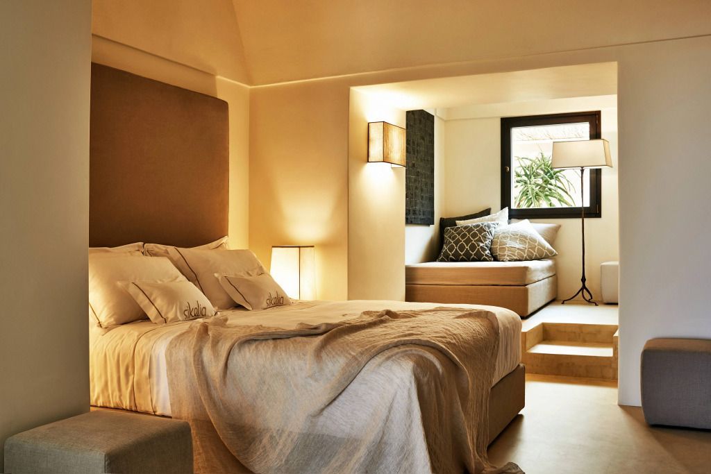 Warmes Schlafzimmer mit bequemen Bett und Sitzgelegenheit am Fenster.