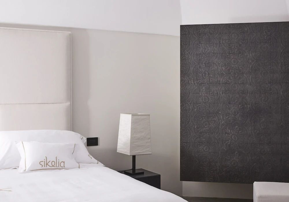 Modernes Schlafzimmer mit weißem Kopfteil und Kunst an der Wand.