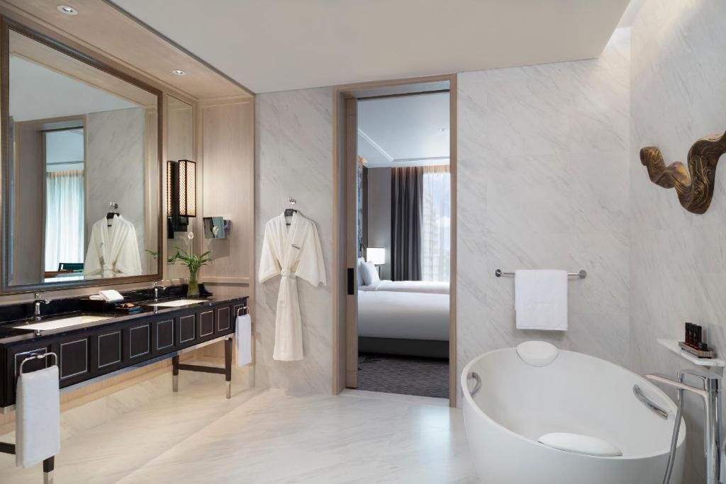 Badezimmer mit freistehender Badewanne und Blick ins Schlafzimmer