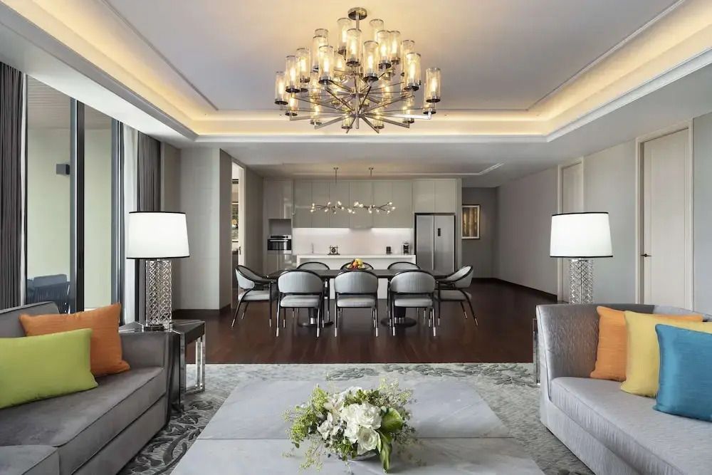 Geräumiges Wohnzimmer mit eleganter Beleuchtung und moderner Küche im Hintergrund.