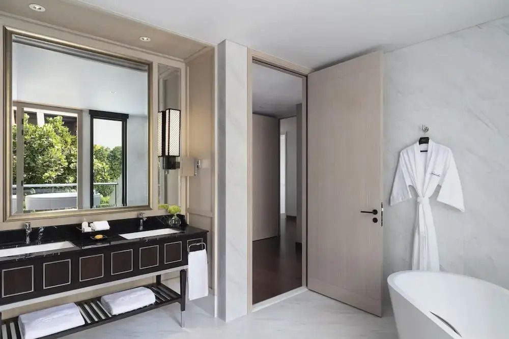 Badezimmer mit schwarzem Waschtisch und weißer Bademantelgarnitur im Sindhorn Kempinski Hotel.