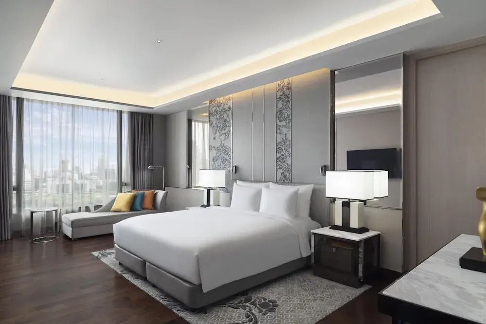 Helles Schlafzimmer der Sindhorn Royal Suite mit Kingsize-Bett und Stadtblick.