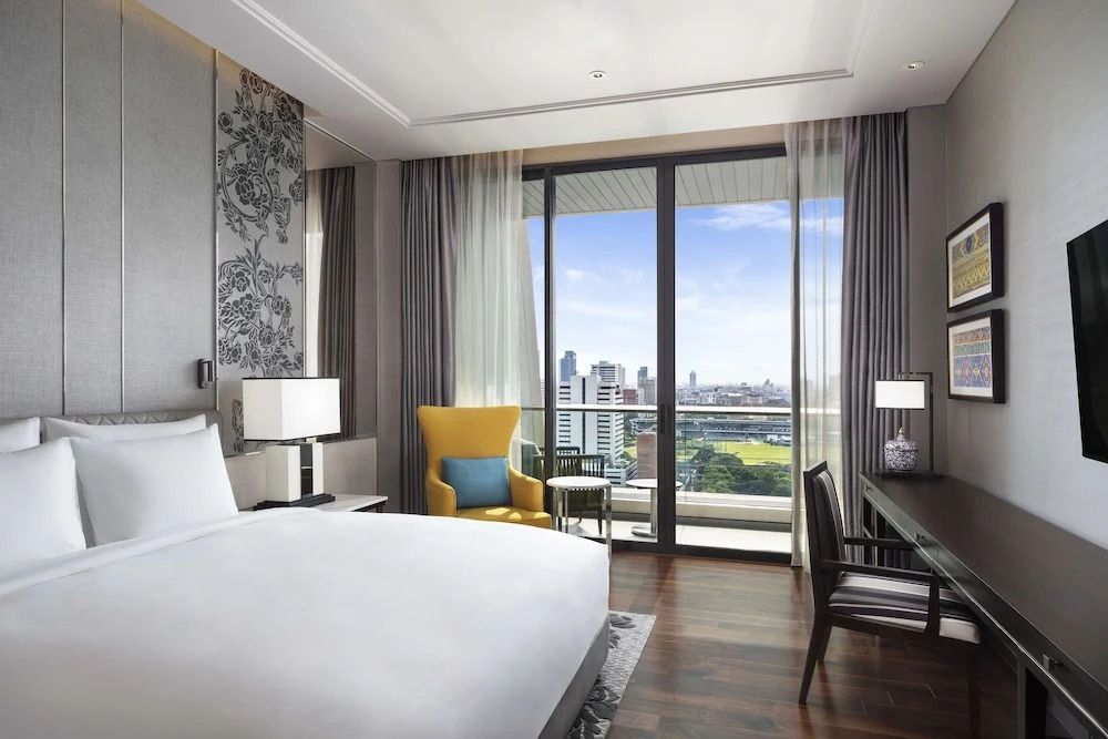 Elegantes Schlafzimmer mit großem Fenster und Stadtblick im Sindhorn Suite Hotelzimmer.