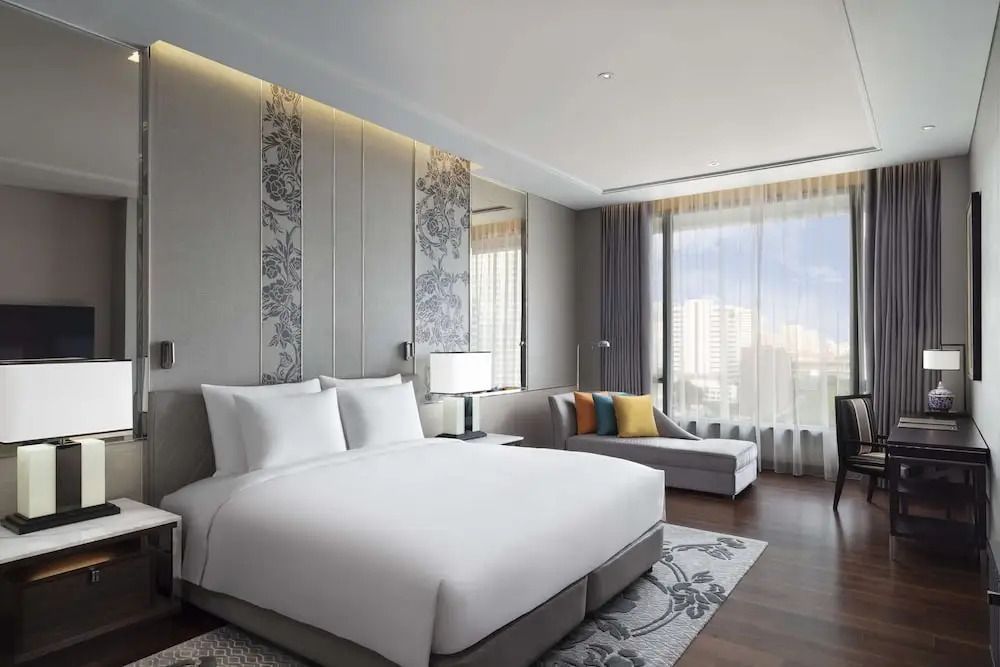 Modernes Schlafzimmer mit Doppelbett und großer Fensterfront im Sindhorn Suite Zimmer.