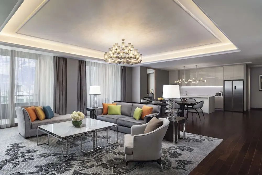 Geräumiges Wohnzimmer der Sindhorn Suite mit modernem Design und Kronleuchter.
