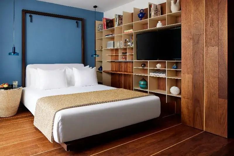 Elegantes Premium Doppelzimmer mit weißem Bett, blauer Wand und Bücherregal.
