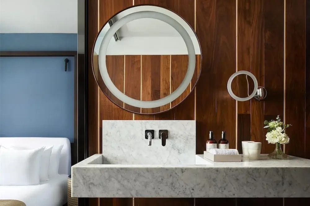 Luxuriöses Badezimmer mit Marmorwaschbecken und hölzerner Wandverkleidung.