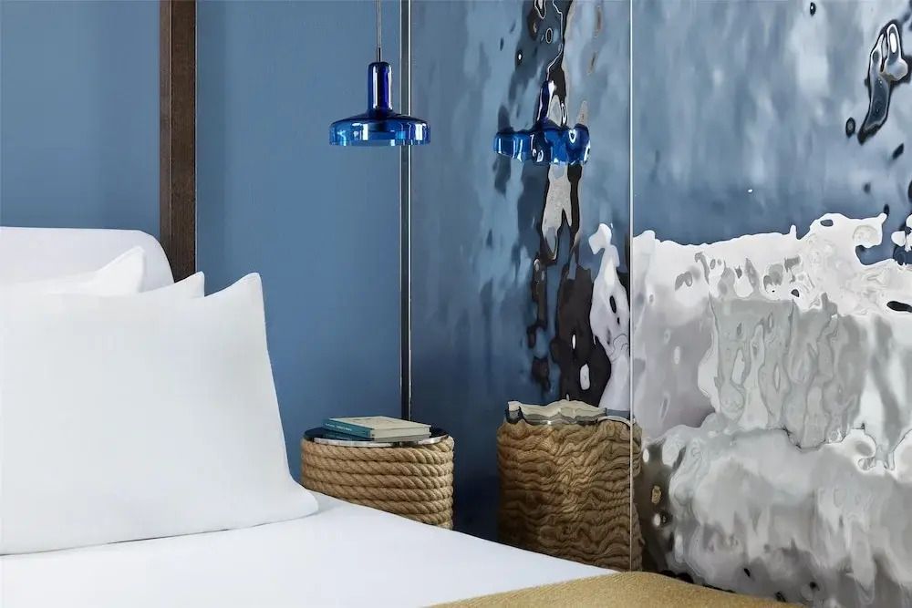 Detailansicht eines Bettes mit blauer Hängelampe und moderner Wanddekoration