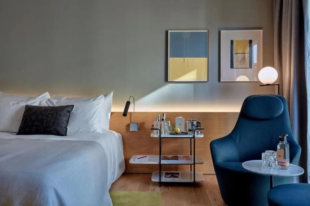 Nachttisch mit Designerlampen und Kunstwerken an der Wand neben dem Bett