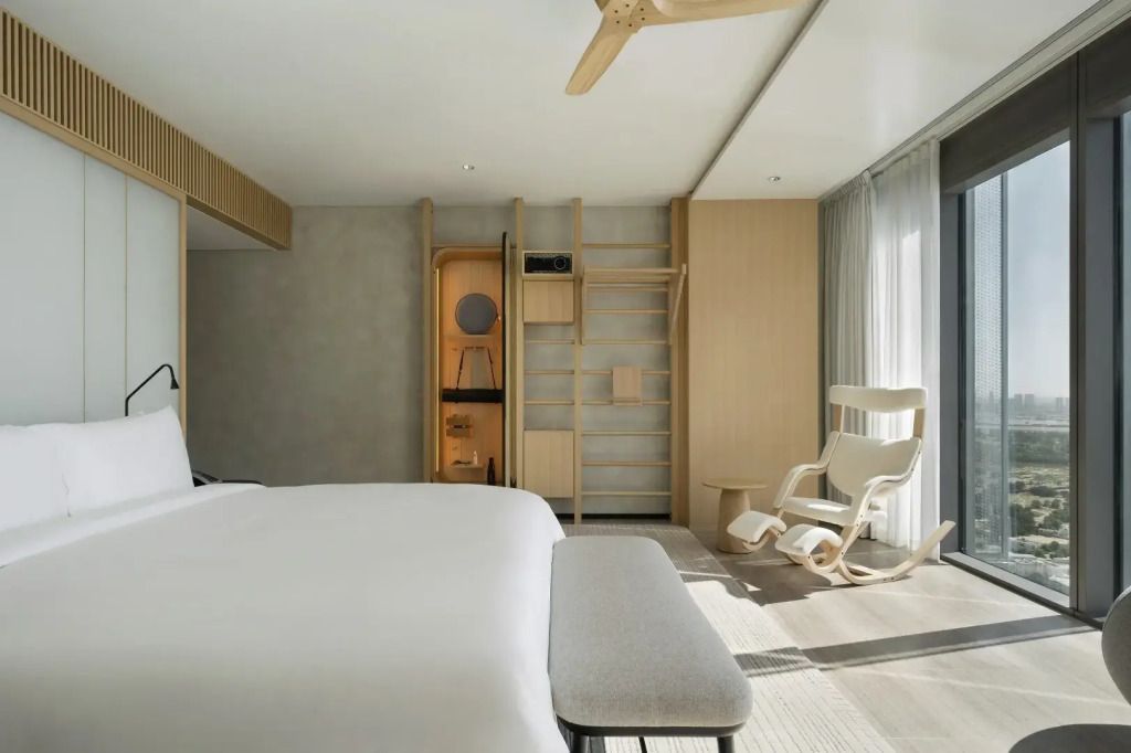 Helles Zimmer mit Doppelbett und Schaukelstuhl neben großen Fenstern