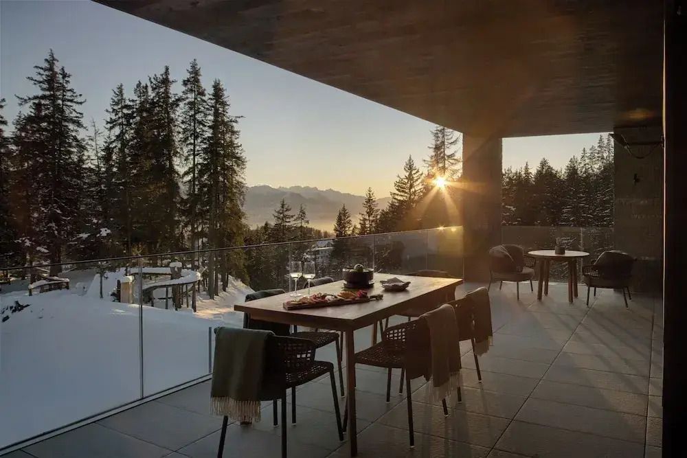Terrasse mit Esstisch und majestätischem Alpenpanorama bei Sonnenuntergang.