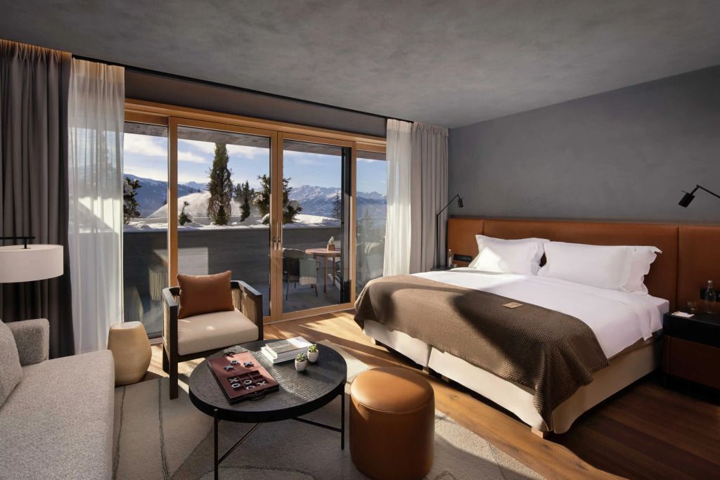 Suite mit Doppelbett und Bergblick von Balkon, stilvolle Möblierung.