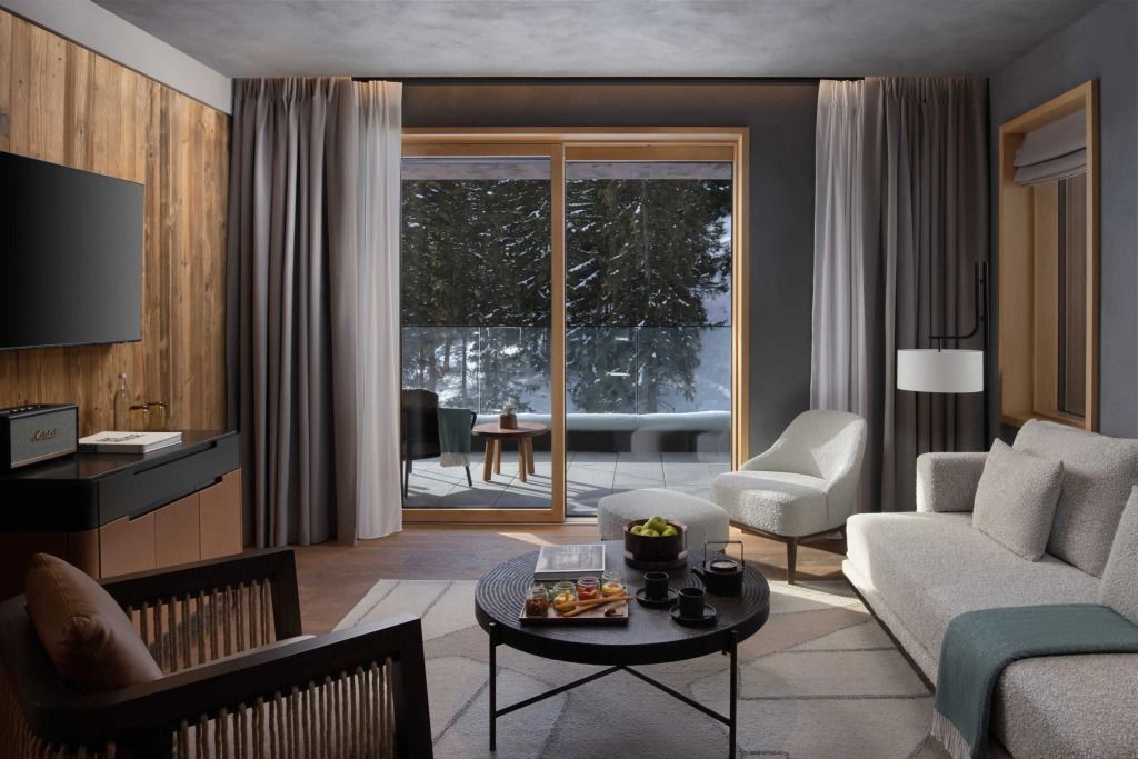 Suite mit bodentiefen Fenstern und Schneesicht, gemütliche Sitzmöbel.