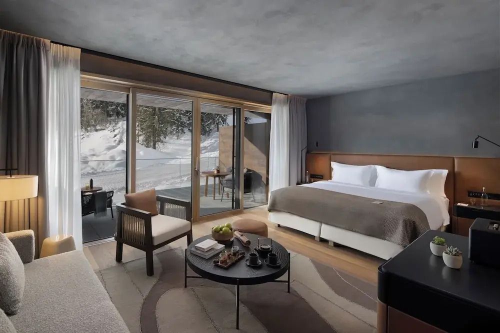 Großzügiges Hotelzimmer mit Fensterfront zum Balkon und Winterlandschaft