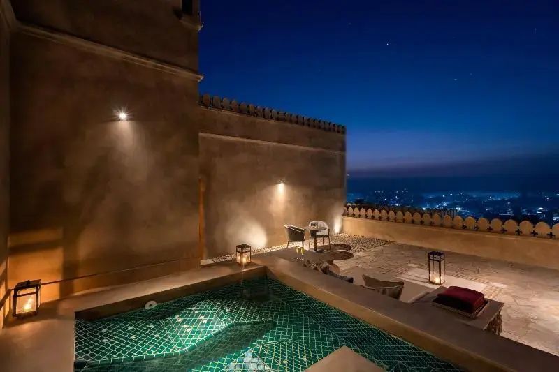 Nachts beleuchtete Terrasse mit kleinem Pool und Aussicht auf die Stadt