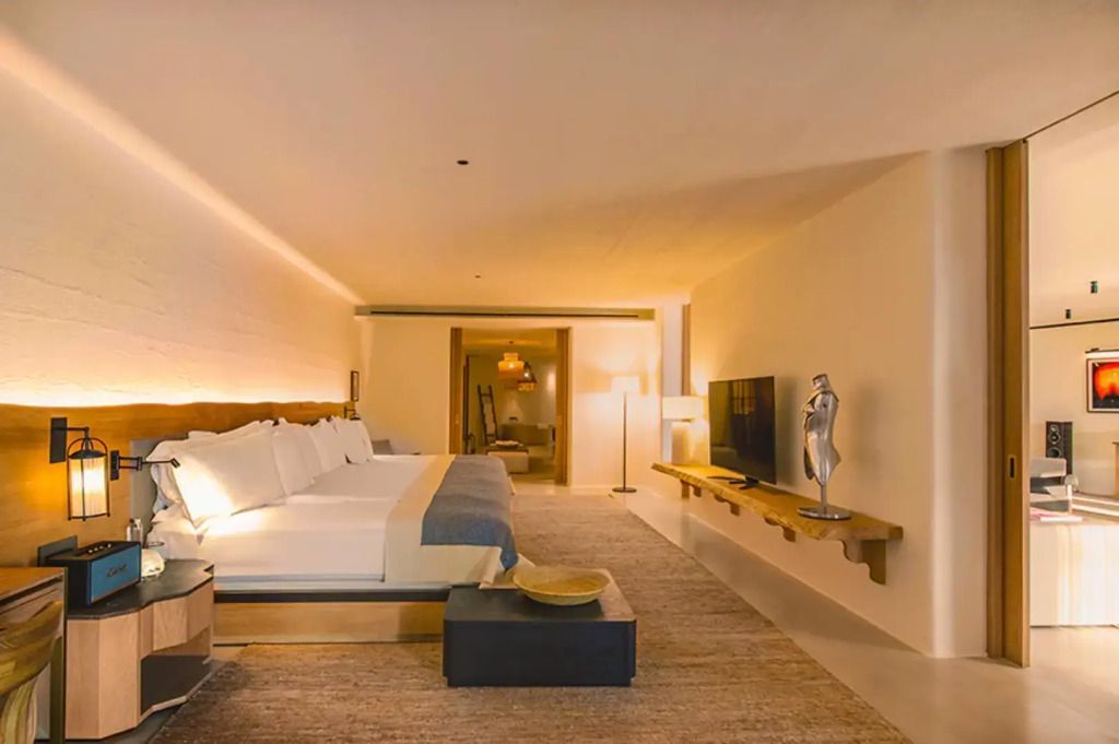 Großzügiges Zimmer mit Bett, Wandregal und Fernseher in natürlichem Licht