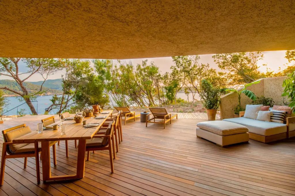 Terrasse mit Holzboden, Sonnenliegen und Esstisch mit Meerblick