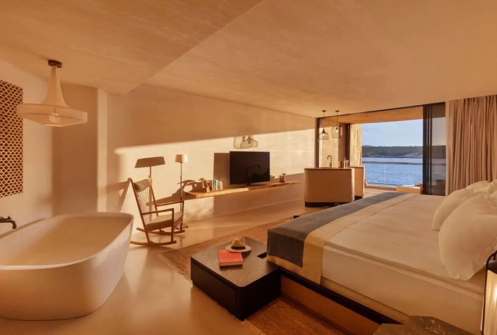 Helles Zimmer mit Badewanne und Blick auf das Meer aus einem großen Fenster