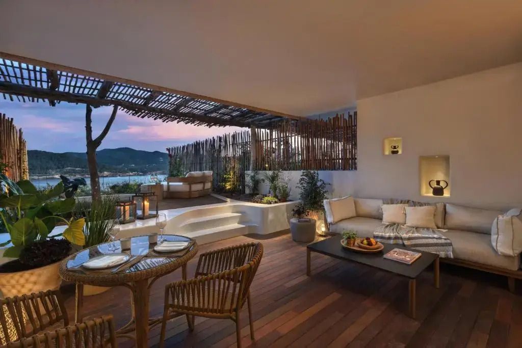 Beleuchtete Terrasse am Abend mit gemütlicher Sitzecke und Blick aufs Meer, ideal für romantische Stunden.
