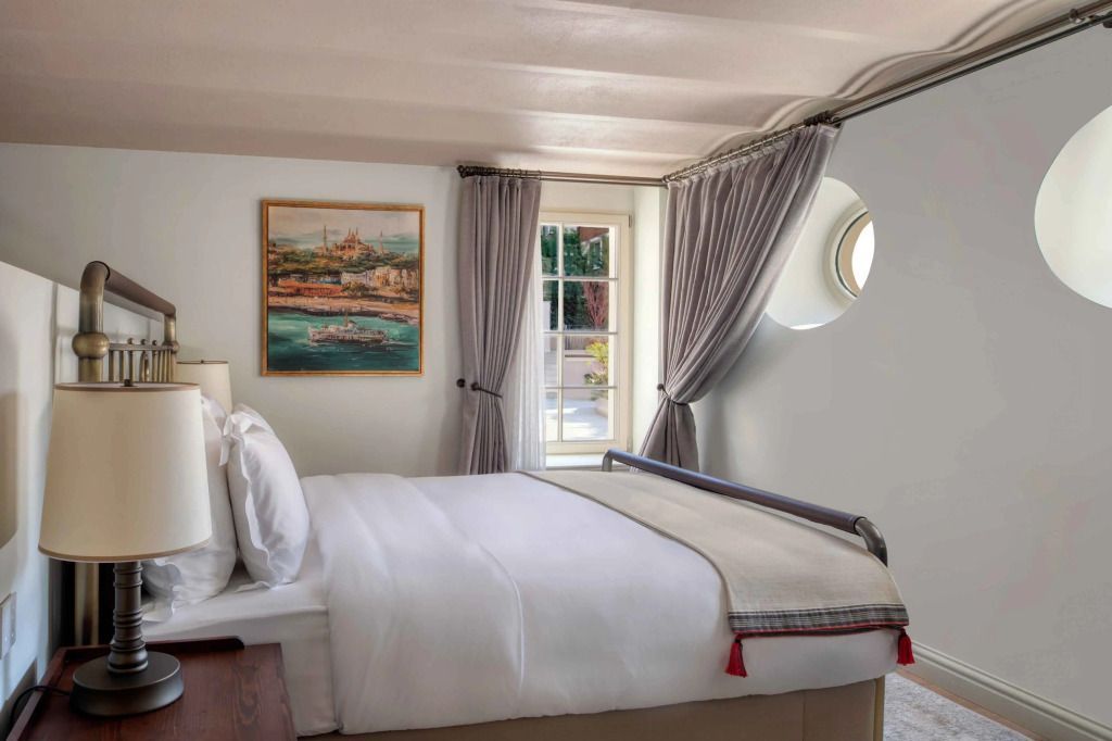 Gemütliches Schlafzimmer mit großem Fenster und Kunstwerk über dem Bett