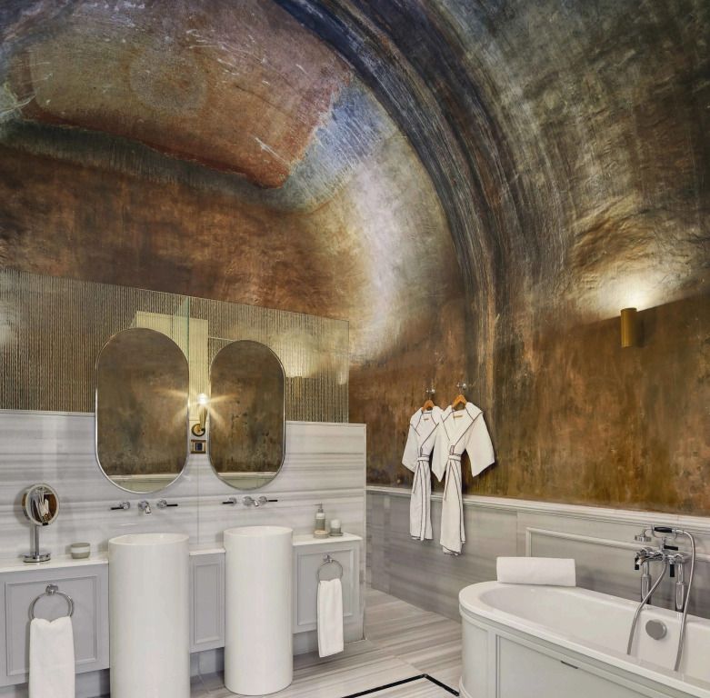 Luxuriöses Badezimmer mit runden Spiegeln und freistehender Badewanne unter Gewölbedecke