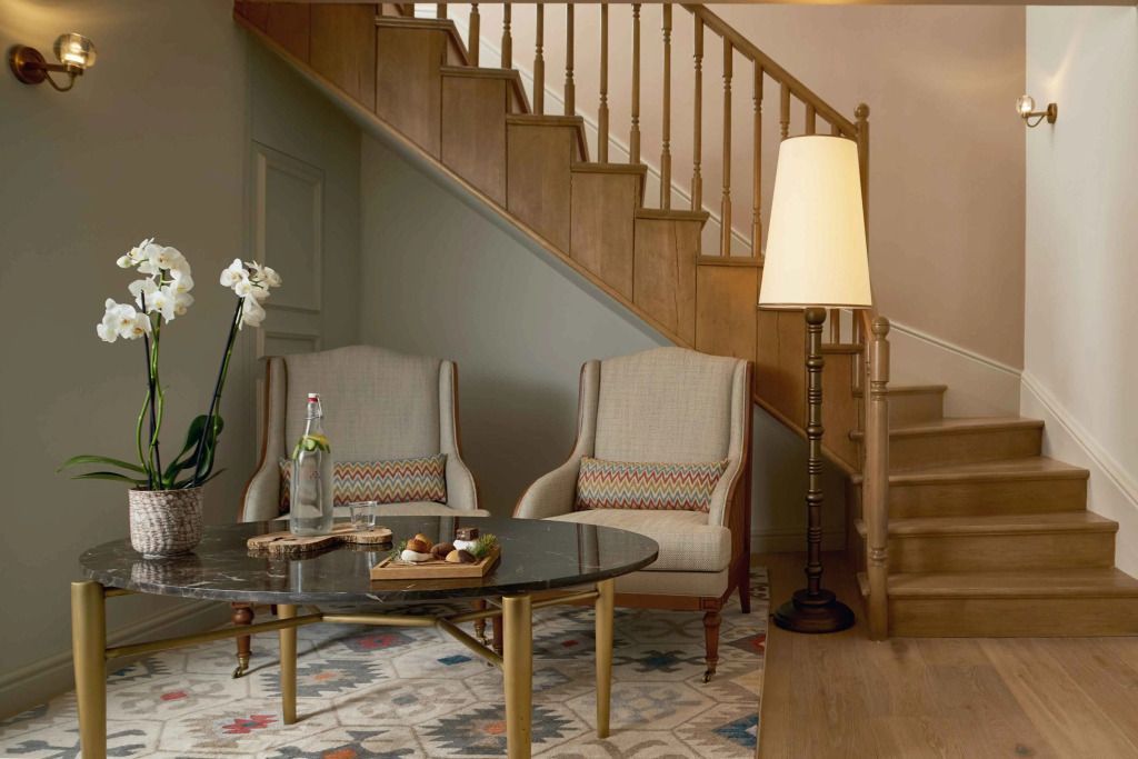 Elegante Sitzecke mit bequemen Sesseln und stilvollem Tisch neben Treppe
