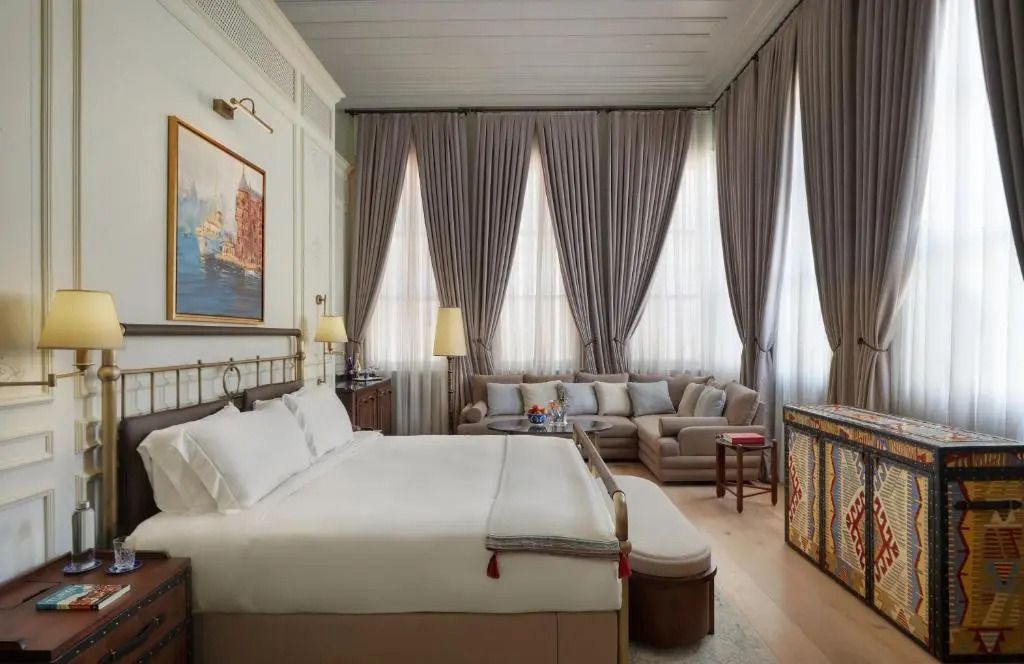 Großzügiges Zimmer mit gemütlicher Sitzecke und eleganten Vorhängen in der Suite.